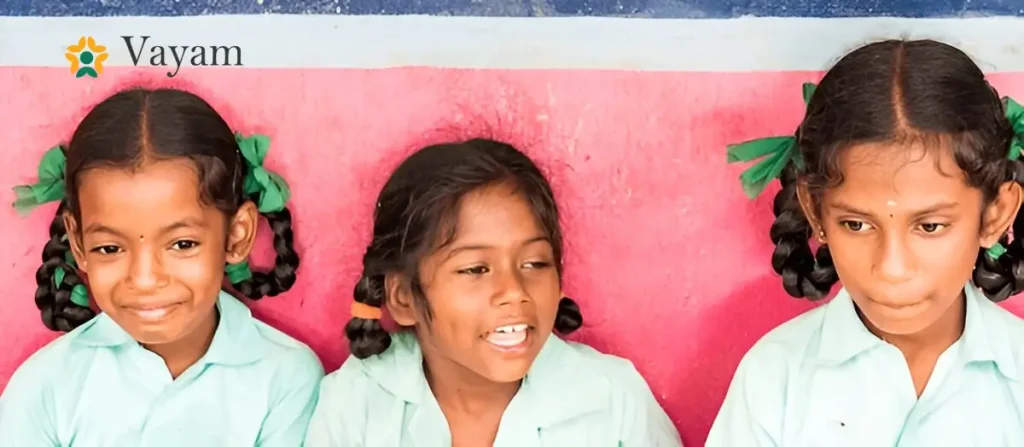 Three cheerful girls pose in front of a pink wall, representing the joy and potential of supporting girl's dream.