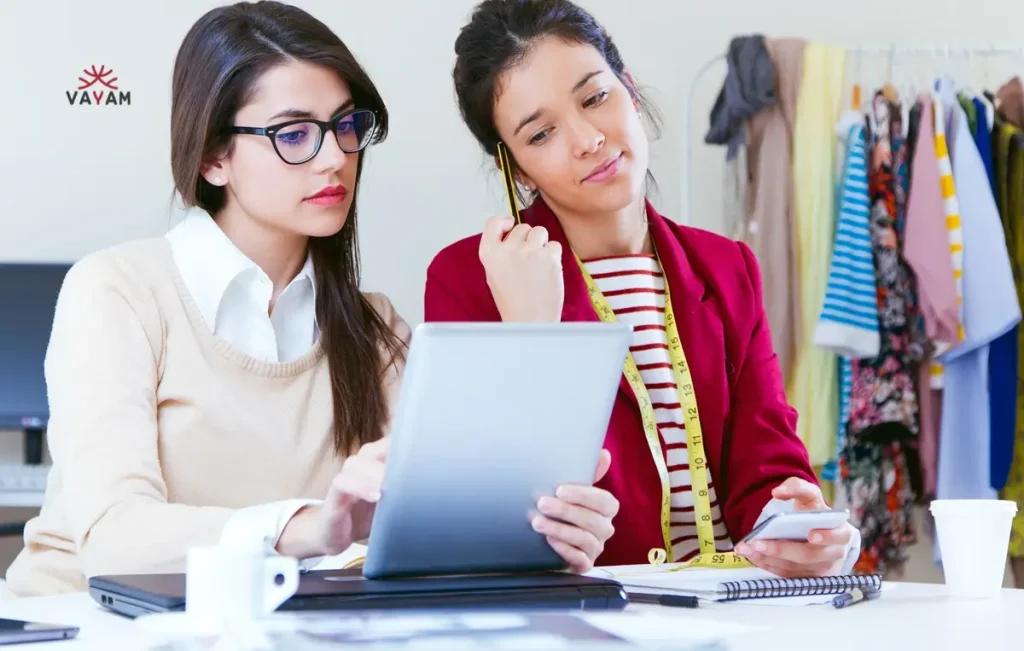 Two women in an office examine a tablet, illustrating the impact of support on girls journeys from orphan to entrepreneur.