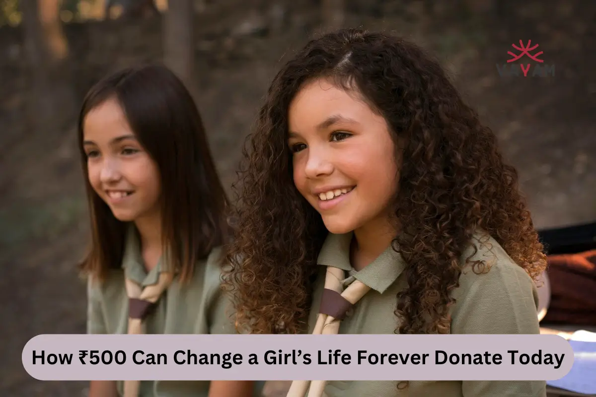 Two young girls in green shirts and ties sit on a bench, symbolizing hope and the impact of donations on their futures.