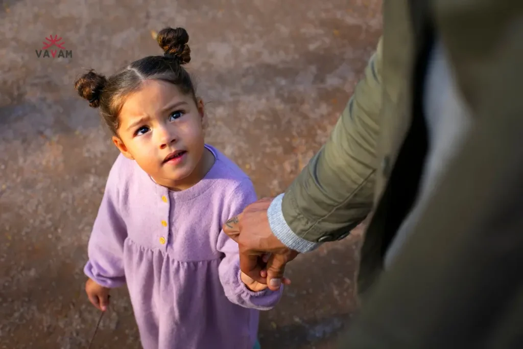 A young girl joyfully holds the hand of a man, symbolizing hope and connection in the context of adopt a girl child in India.