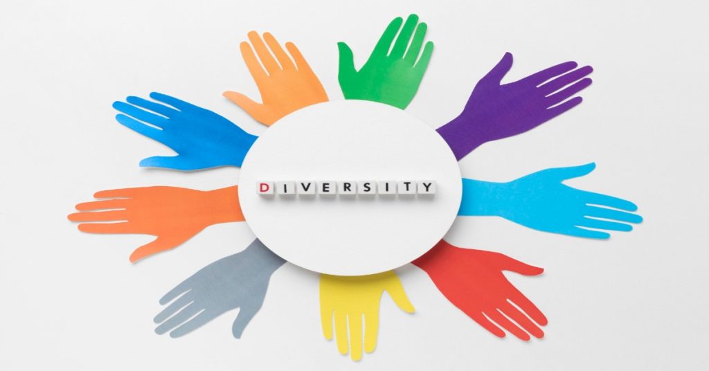 Multicolored hands encircle the word diversity, symbolizing CSR trend focused on Diversity, Equity, and Inclusion (DEI).