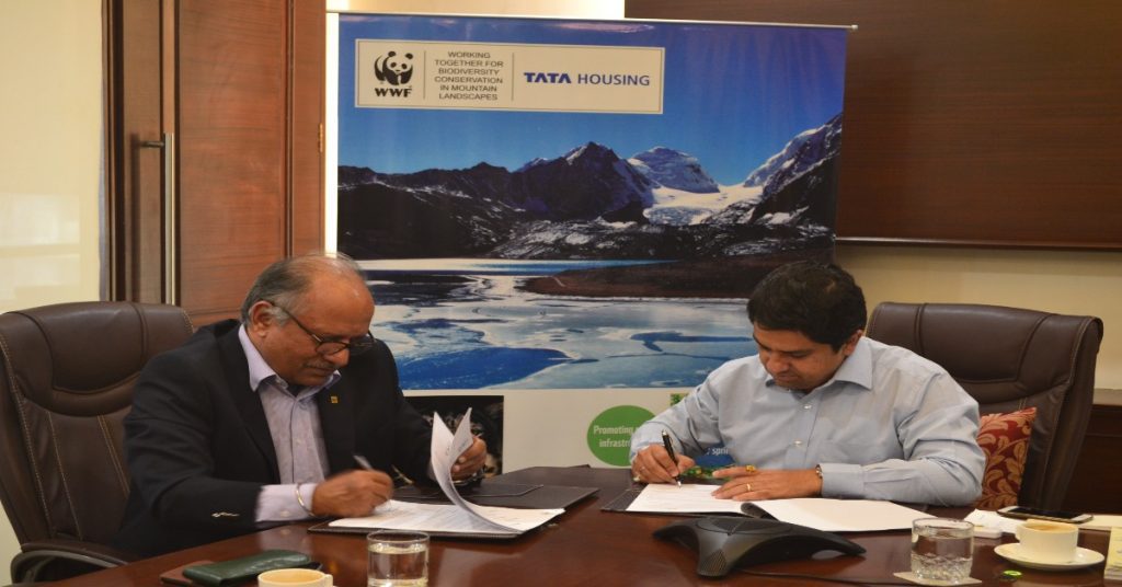 Two men at a table signing papers, representing a CSR partnership between Tata Motors and WWF.