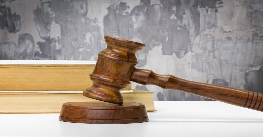  Judge's gavel resting on books on a wooden table, symbolizing laws against child labor in India.