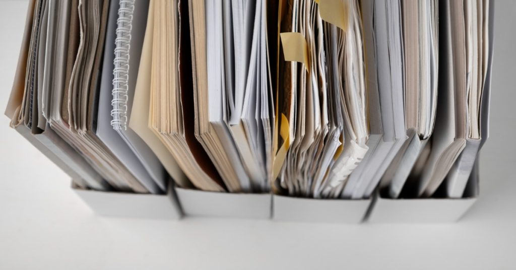 A stack of papers on a white surface, representing the documents needed for RTE admission under EWS category.