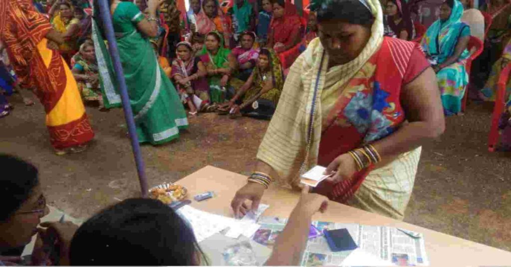 A woman in a sari vote at a booth, highlighting stories of women's empowerment through the MGNREGA scheme.