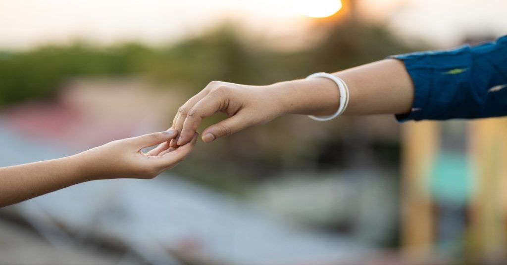 A woman and a child holding hands to represent support for child labour survivors.