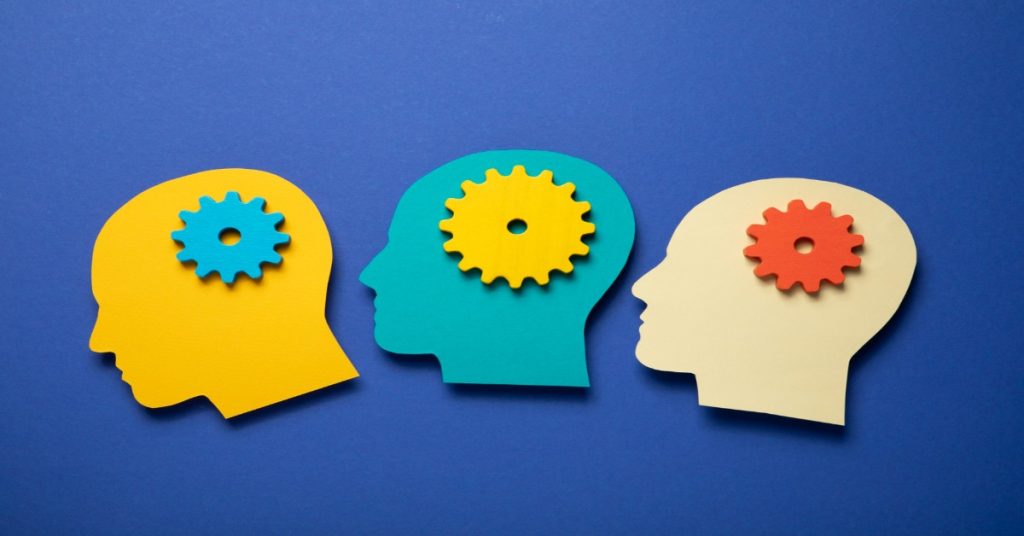 Three colorful heads with gears on their heads, to represent public speaking sharpens critical thinking. 