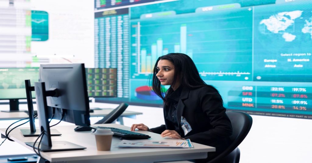 A business-suited woman sitting at a desk with a computer, engaged in skill development through data analytics training.