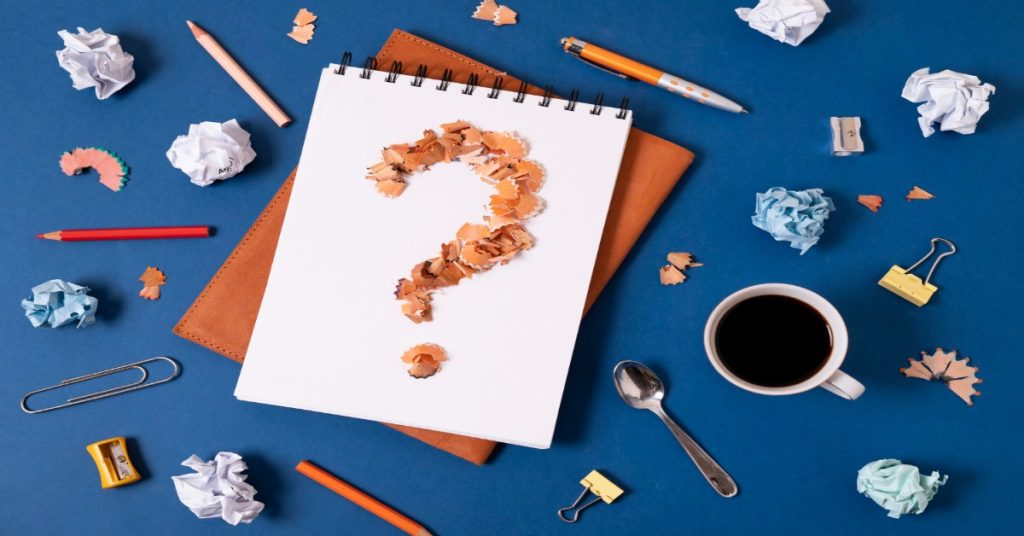 A question mark on a notepad surrounded by office supplies, symbolizing key survey questions.