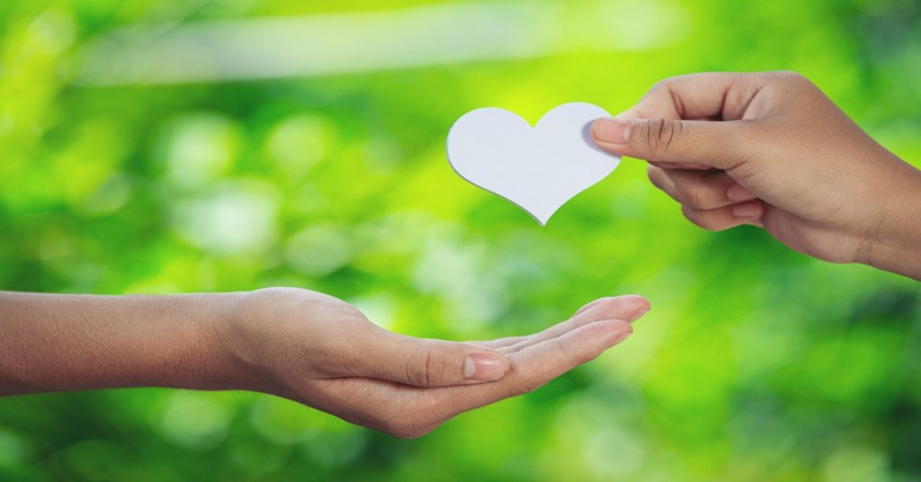 Two hands hold a paper heart against a green background, symbolizing millennials' emotional connection to CSR.