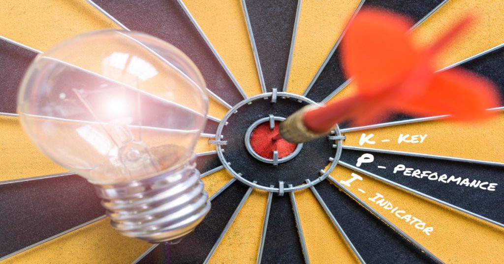 A dart hitting a lightbulb on a dartboard, representing CSR reporting as a tool for evaluating Key Performance Indicators (KPIs).