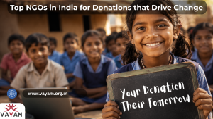 A smiling girl holds a chalkboard reading "Your Donation, Their Tomorrow" in front of a group of children in school uniforms, promoting Vayam Top NGOs in India for Donations that Drive Change